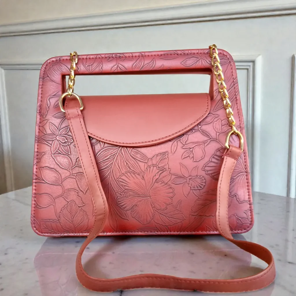 Brick red embossed floral mini crossbody bag displayed with long gold chain and shoulder pad for comfortable wearing