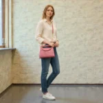 Model wearing brick red embossed floral mini crossbody bag across body showing size fit and styling for daily use