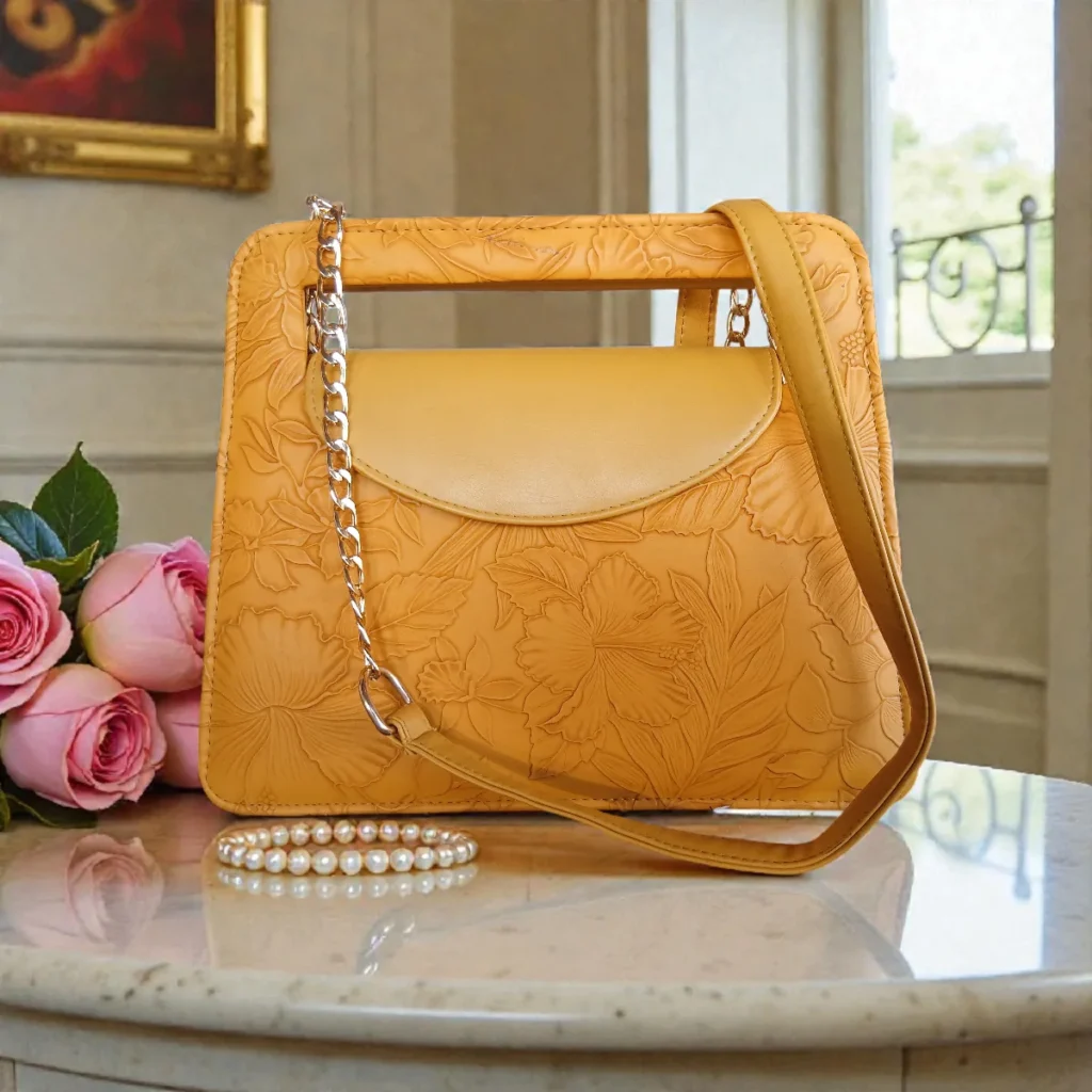 Embossed floral mustard yellow mini crossbody bag with chain strap on table
