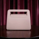 Back view of soft pink embossed floral mini carry crossbody handbag showing clean smooth surface and built-in handle