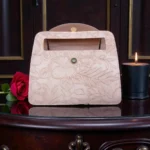 Soft pink embossed floral mini carry crossbody handbag showing inner flap and magnetic closure with floral detailing on table