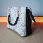 Embossed koi leather shoulder handbag in ice blue, back and side view on display surface