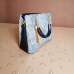 Embossed koi leather shoulder handbag in ice blue, angled view on floral textured surface
