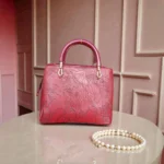 Front view of embossed maroon koi leather shoulder handbag with tassel