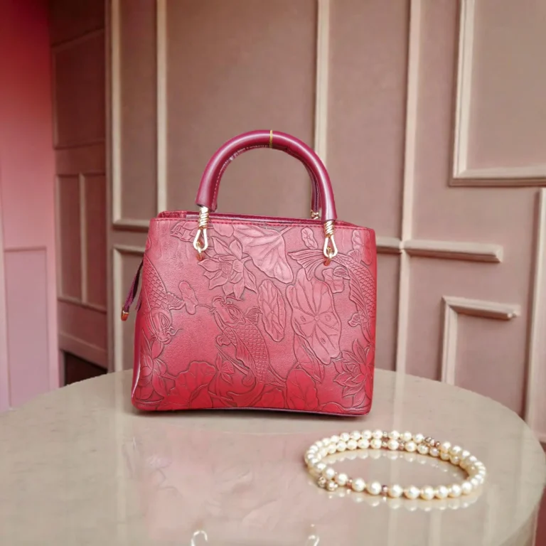 Front view of embossed maroon koi leather shoulder handbag with tassel