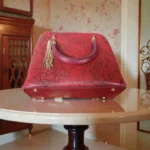 Bottom view of embossed maroon koi leather handbag with metal feet