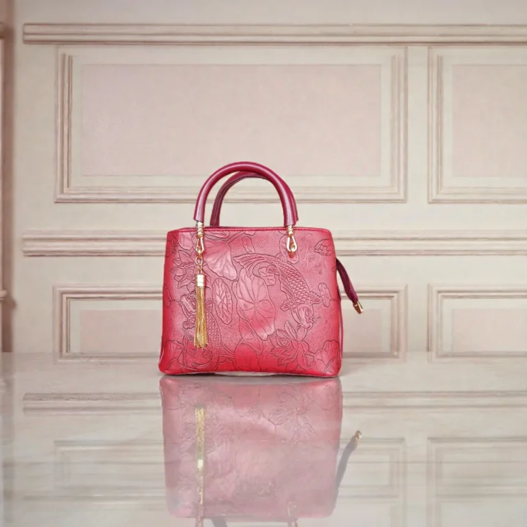 Embossed maroon leather handbag with koi and floral pattern on a table