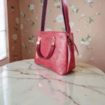 Back side angled view of embossed maroon koi leather handbag with shoulder strap