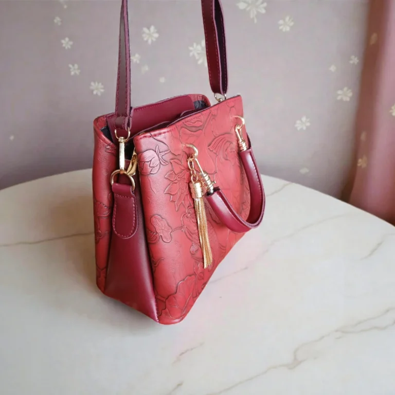 Side view of embossed maroon koi leather handbag showing strap and tassel
