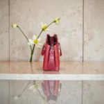 Side profile of embossed maroon koi leather handbag showing three compartments