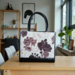 back view of Black floral printed handbag placed on a table with indoor background