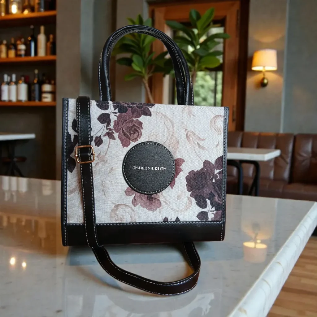 Fabric floral printed crossbody handbag in black color placed on a table
