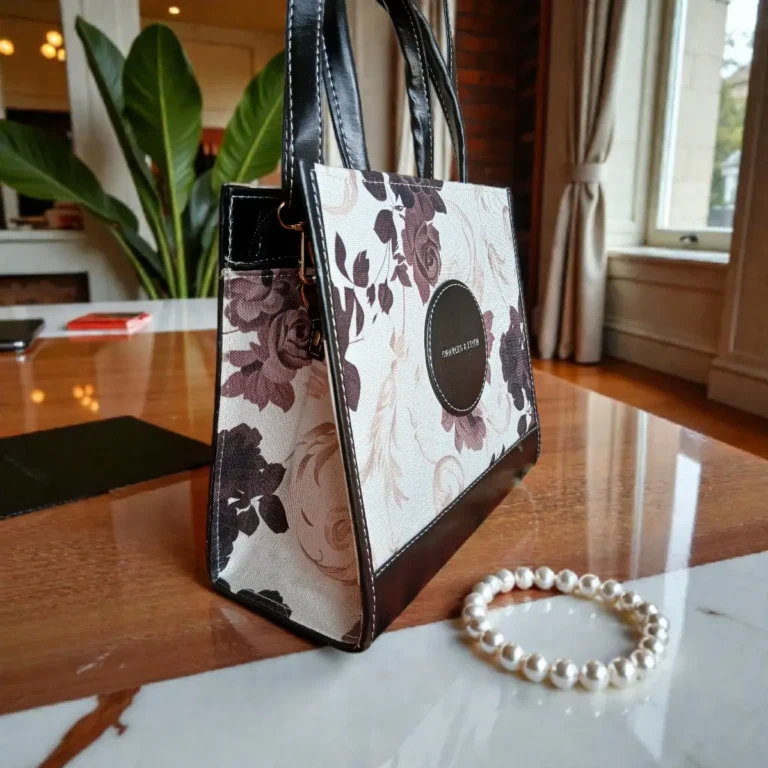 Angled side view showing depth of black floral printed handbag
