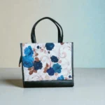 Green fabric floral printed handbag showing back side with smooth leather base