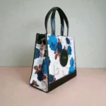 Green floral printed crossbody handbag with structured side panel and stitched leather edges