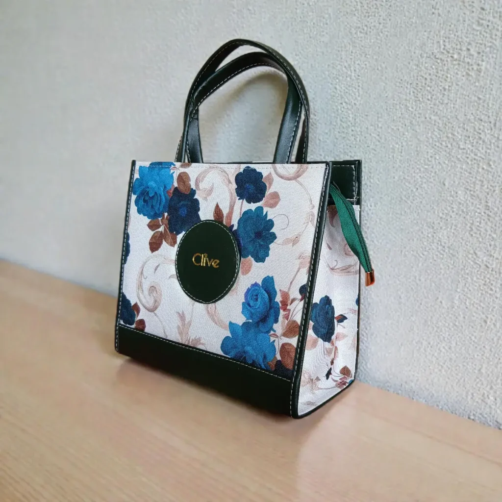 Green fabric floral printed crossbody handbag showing side shape and leather finish details
