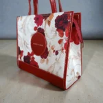 Side view of maroon floral printed crossbody handbag showing depth and shape