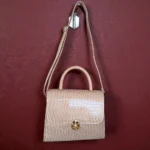 Glossy beige croc handbag hanging by strap