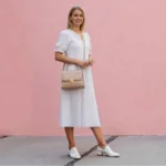 Woman wearing white dress holding glossy beige croc top handle handbag
