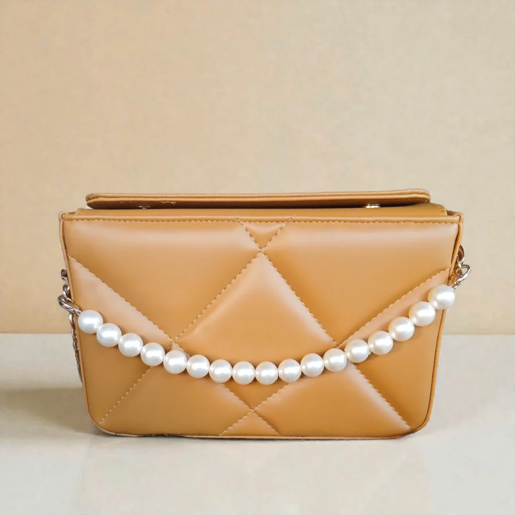 Front view of camel quilted handbag with pearl chain on display