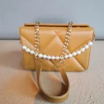 Front view of camel quilted crossbody handbag with pearl chain and gold chain strap