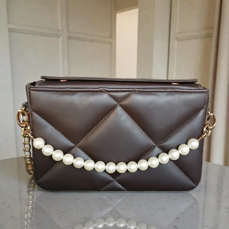 Front view of coffee brown quilted crossbody bag with pearl chain detai