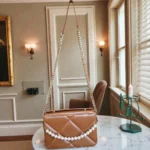 Pearl chain quilted crossbody bag in tan brown hanging by gold chain strap