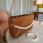 Side view of tan brown quilted crossbody bag with pearl chain and gold hardware