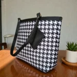 Side view of black and white houndstooth printed tote bag with detachable pouch