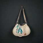 Beige drawstring handbag with long strap displayed on dark background