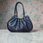 Navy blue handbag showing rounded base and textured finish