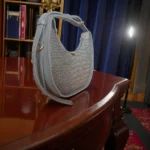 Grey textured crossbody bag with pearl chain side angle view
