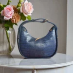 Navy blue textured crossbody bag displayed in boutique setting