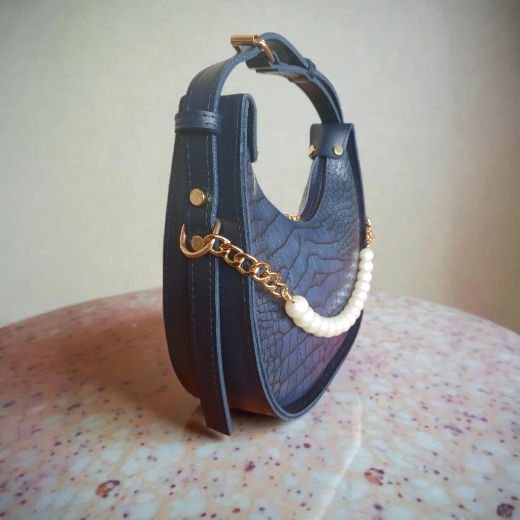 Side view of navy blue crossbody bag with pearl detail