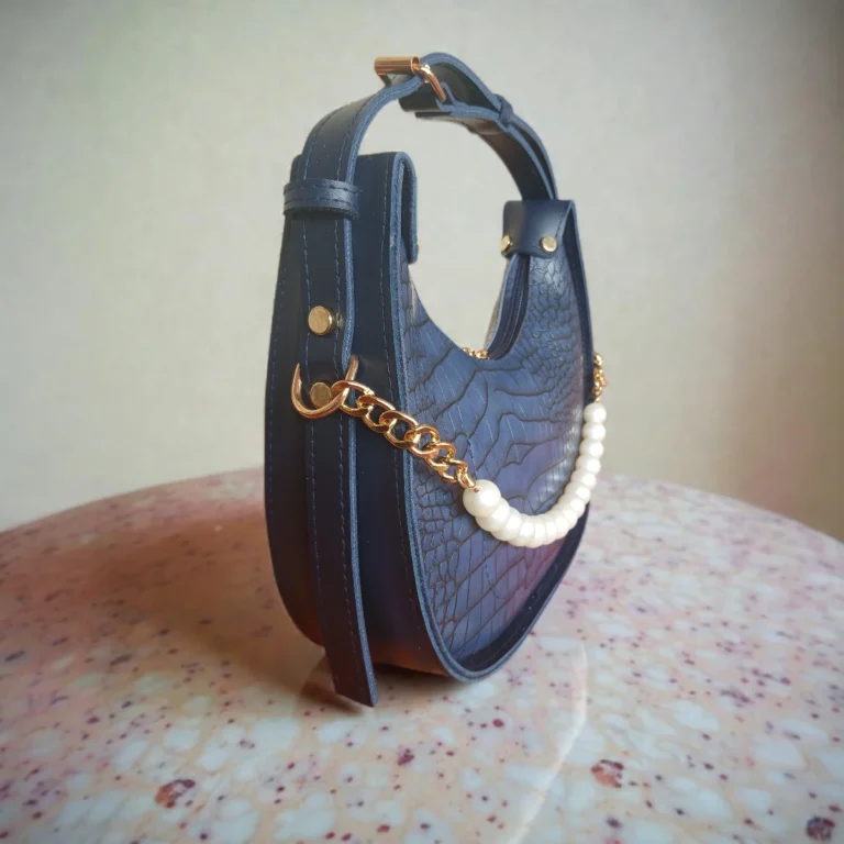 Side view of navy blue crossbody bag with pearl detail