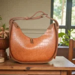 Tan brown textured crossbody bag with smooth back design and adjustable shoulder strap