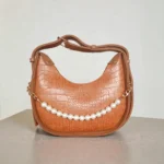 Textured tan brown crossbody bag with pearl chain detail and adjustable strap, front view