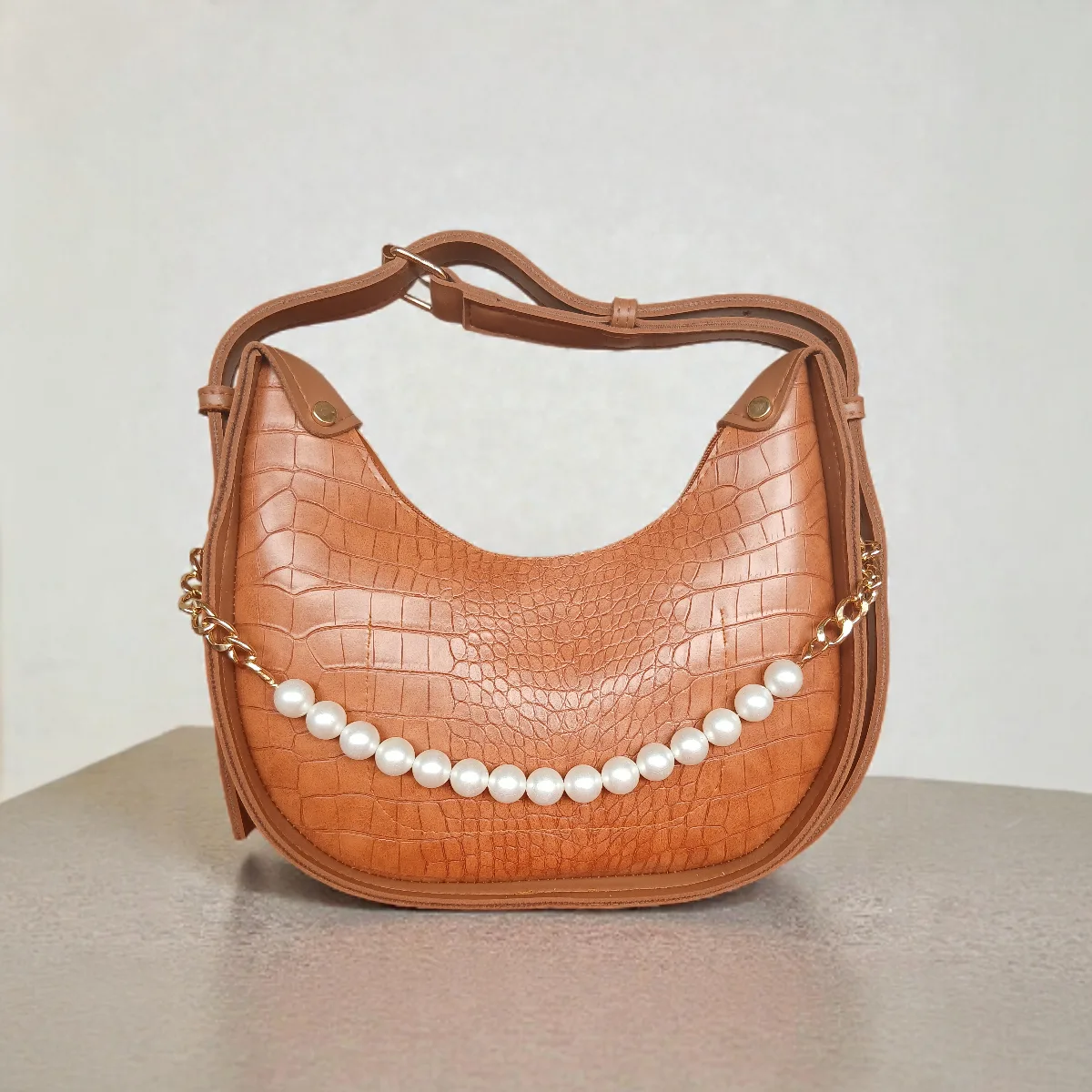 Textured tan brown crossbody bag with pearl chain detail and adjustable strap, front view
