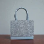 Back view of grey tweed crossbody handbag displaying plain tweed panel
