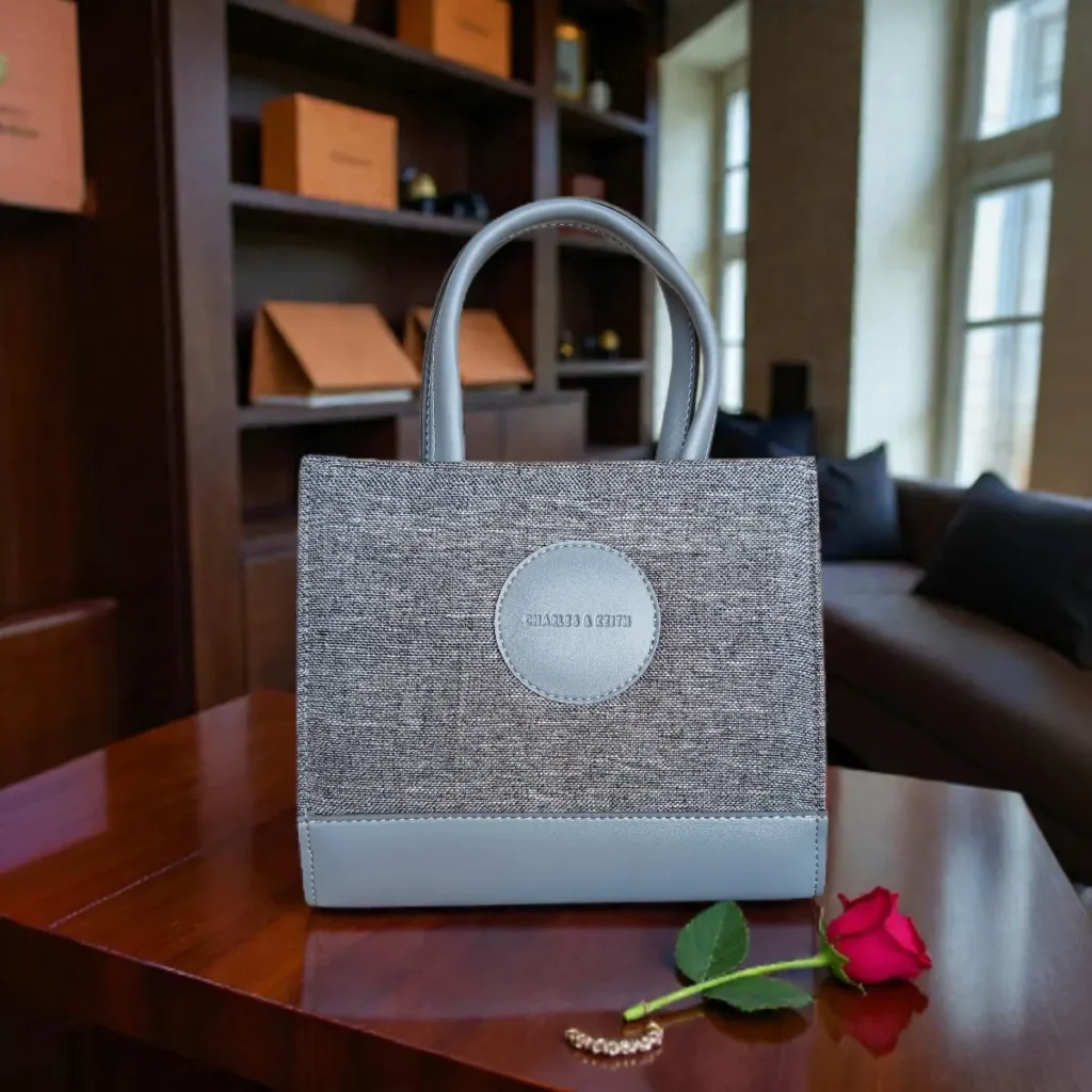 Front view of grey tweed crossbody handbag placed on a wooden table