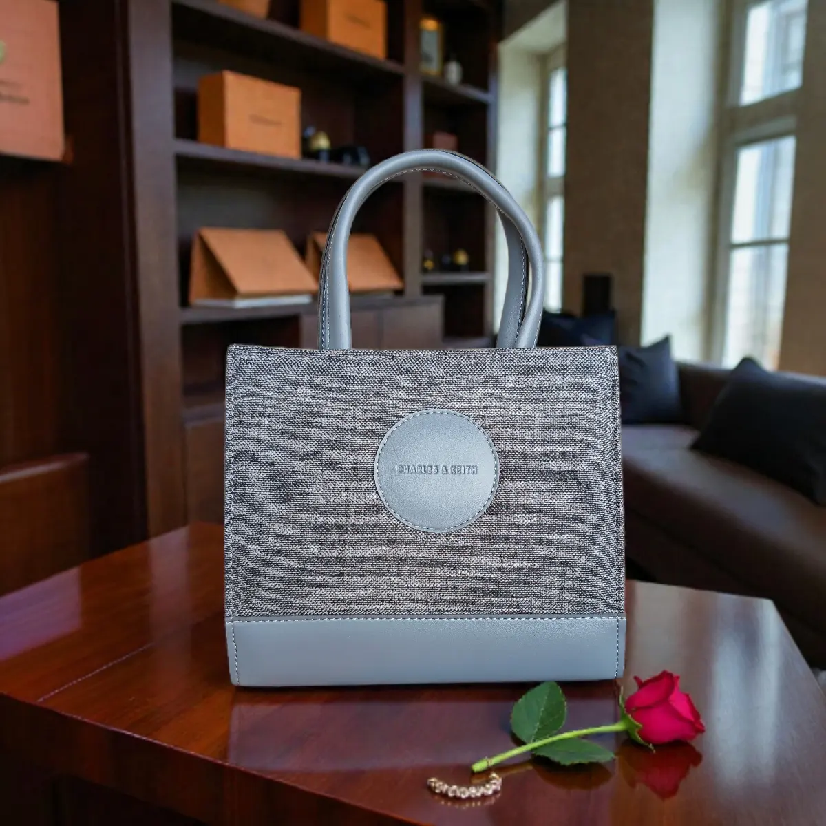 Front view of grey tweed crossbody handbag placed on a wooden table