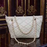 Ivory Cream quilted tote bag front view on wooden table with gold chain straps
