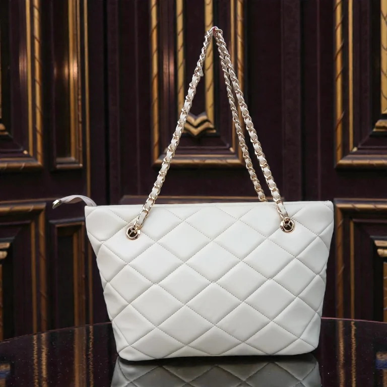 Ivory Cream quilted tote bag front view with double gold chain handles resting on wooden table