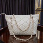 Lifestyle image of woman carrying Ivory Cream quilted chain strap tote bag on shoulder