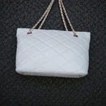 Side profile of pearl white quilted leather tote bag highlighting depth and structured base