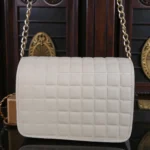 Back side view of embossed grid leather flap chain crossbody bag in ivory white showing square textured pattern