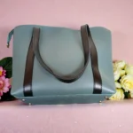 Dusty blue minimal tote handbag bottom view with metal studs and black straps