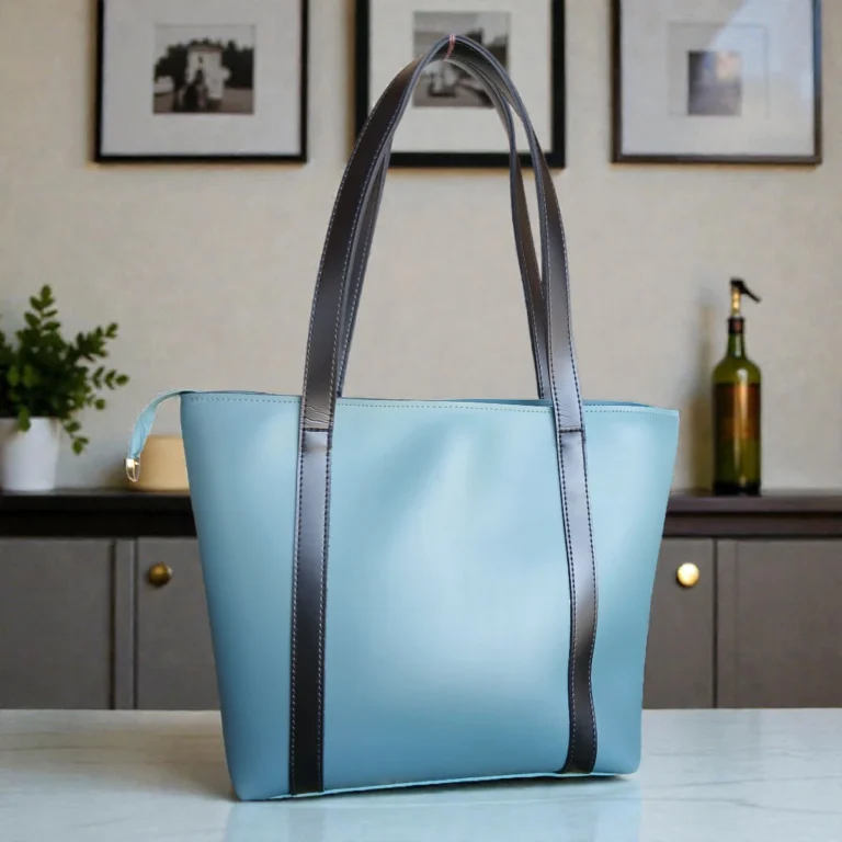 Dusty blue contrast strap tote handbag front view with black double shoulder straps on marble table