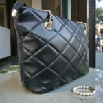 Close up side profile of Classic Quilted Chain Strap Tote Bag – Jet Black showing smooth quilted faux leather surface and polished gold eyelet hardware